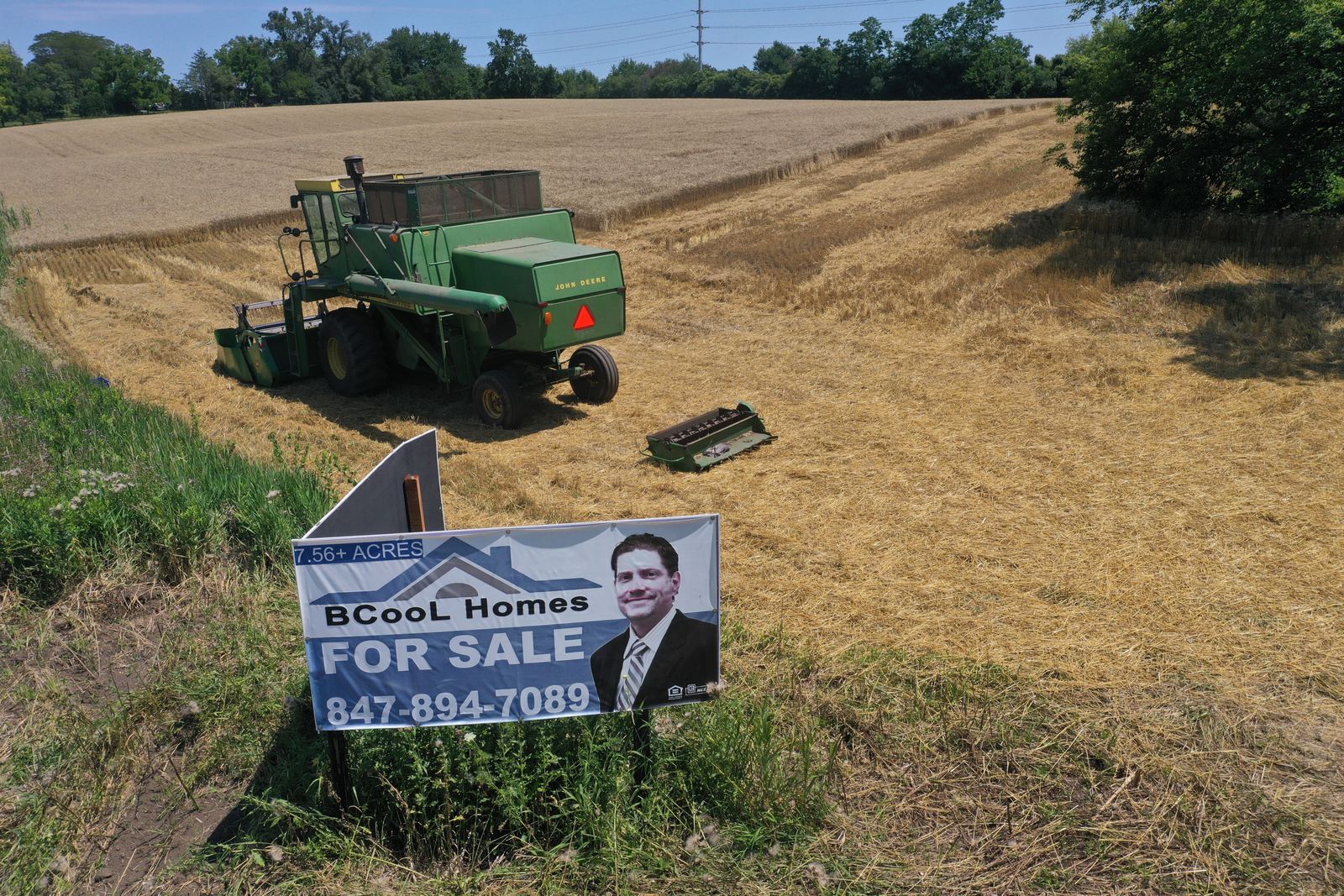 A tractor is seen next to a for sale sign.