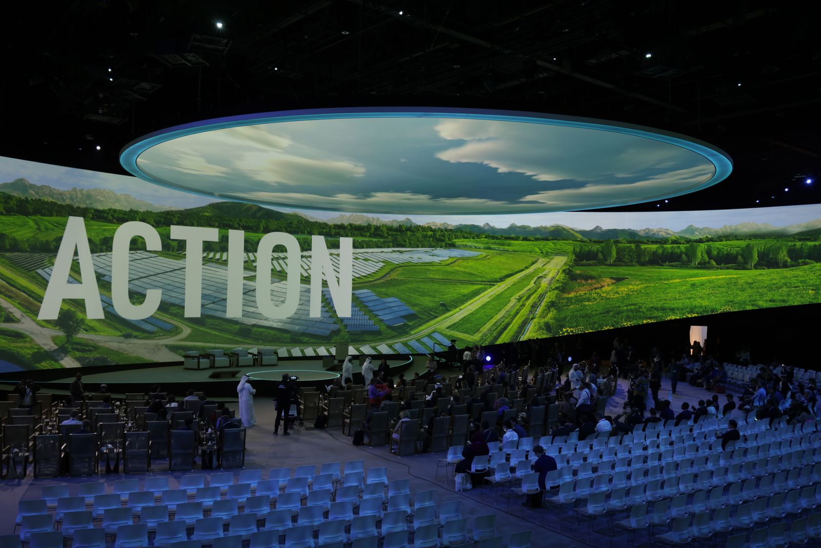 People arrive at a theater where a picture of farmland is projected on a screen with the word &quot;Action.&quot;