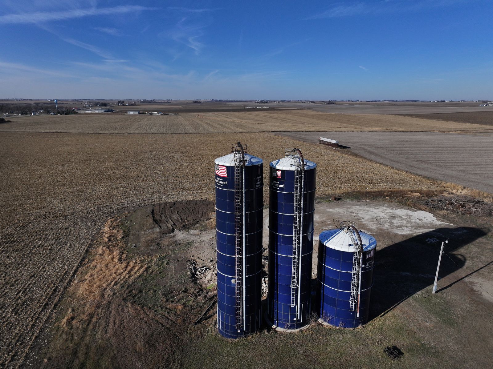 A farm with blue siloes is seen in an aerial shot.