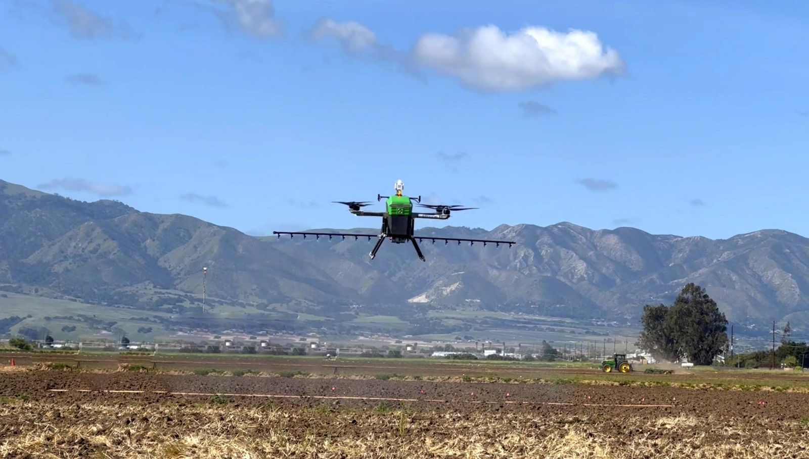 A drone is seen on the ground at the edge of a farm field