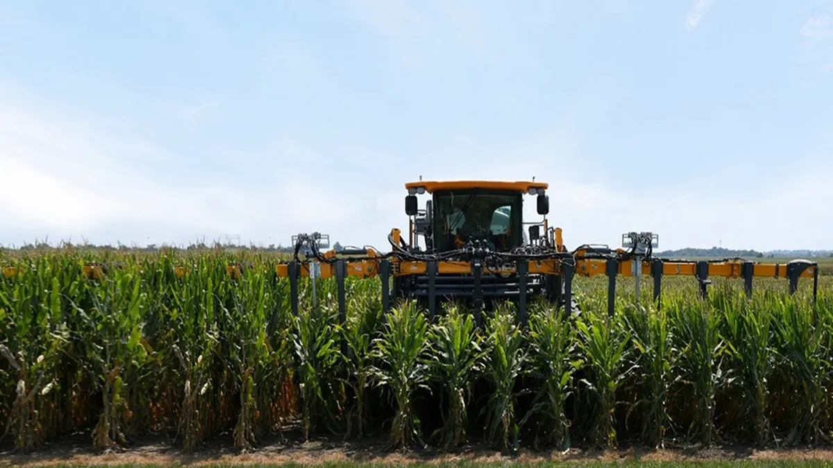 A field sprayer is seen over rows of corn