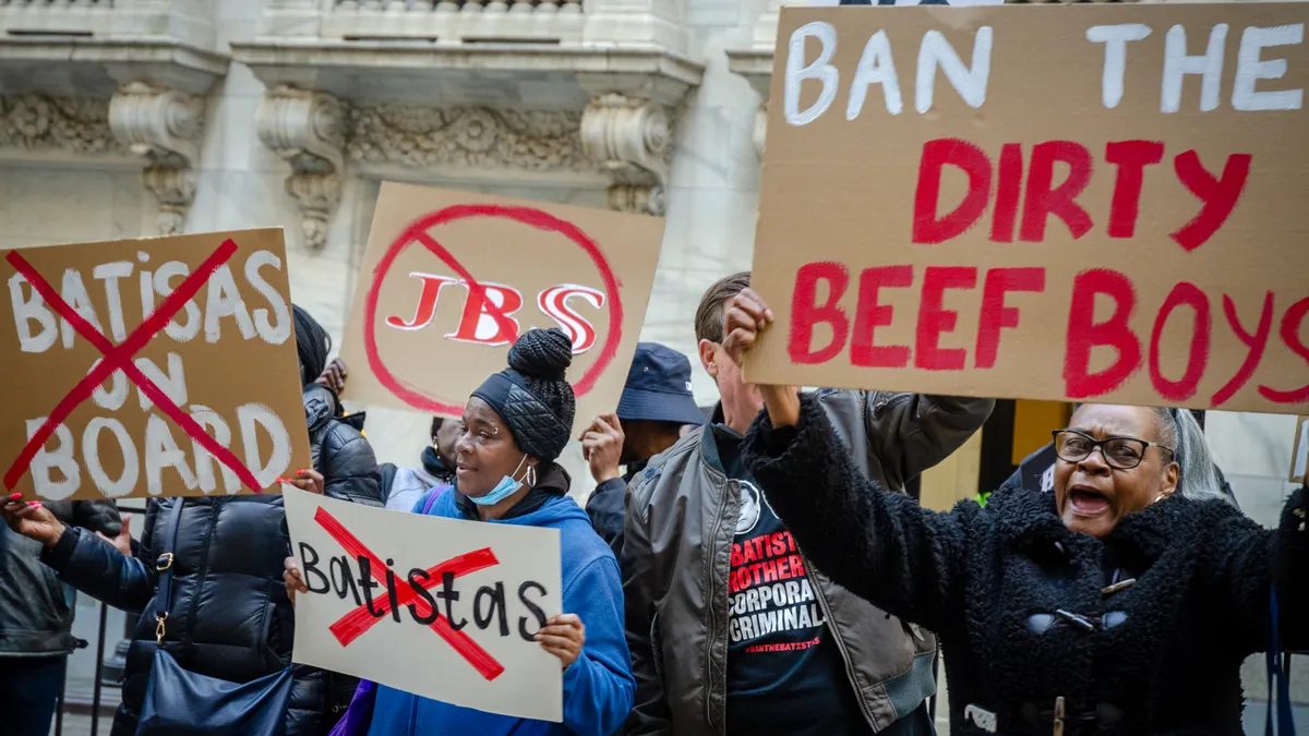 Protesters with signs urging the SEC to reject JBS' planned IPO are seen