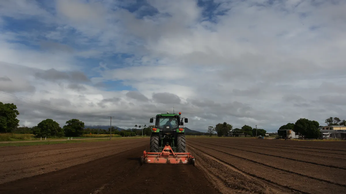 A small tractor is seen in the middle of a field.