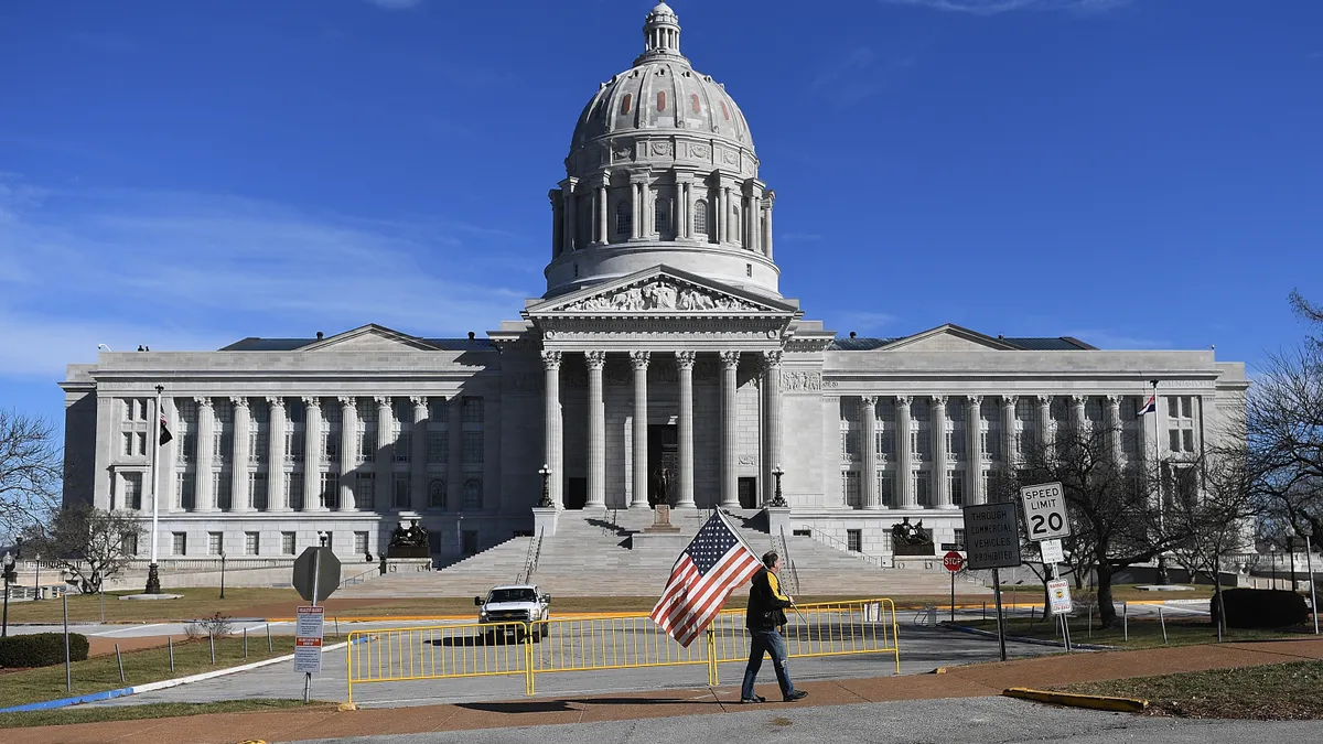 A man waves an American flag as he walks outside the Missouri State Capitol building in Jefferson City.