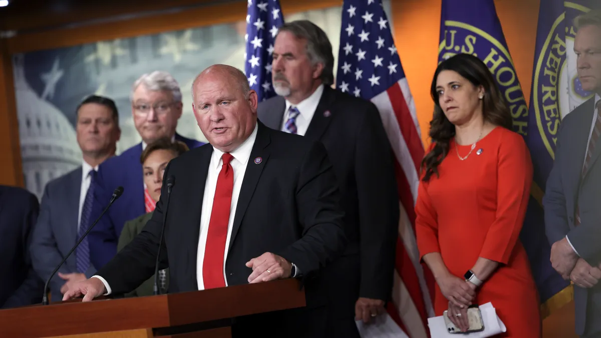 Rep. Glenn Thompson is seen speaking in front of a dais with a group of people behind