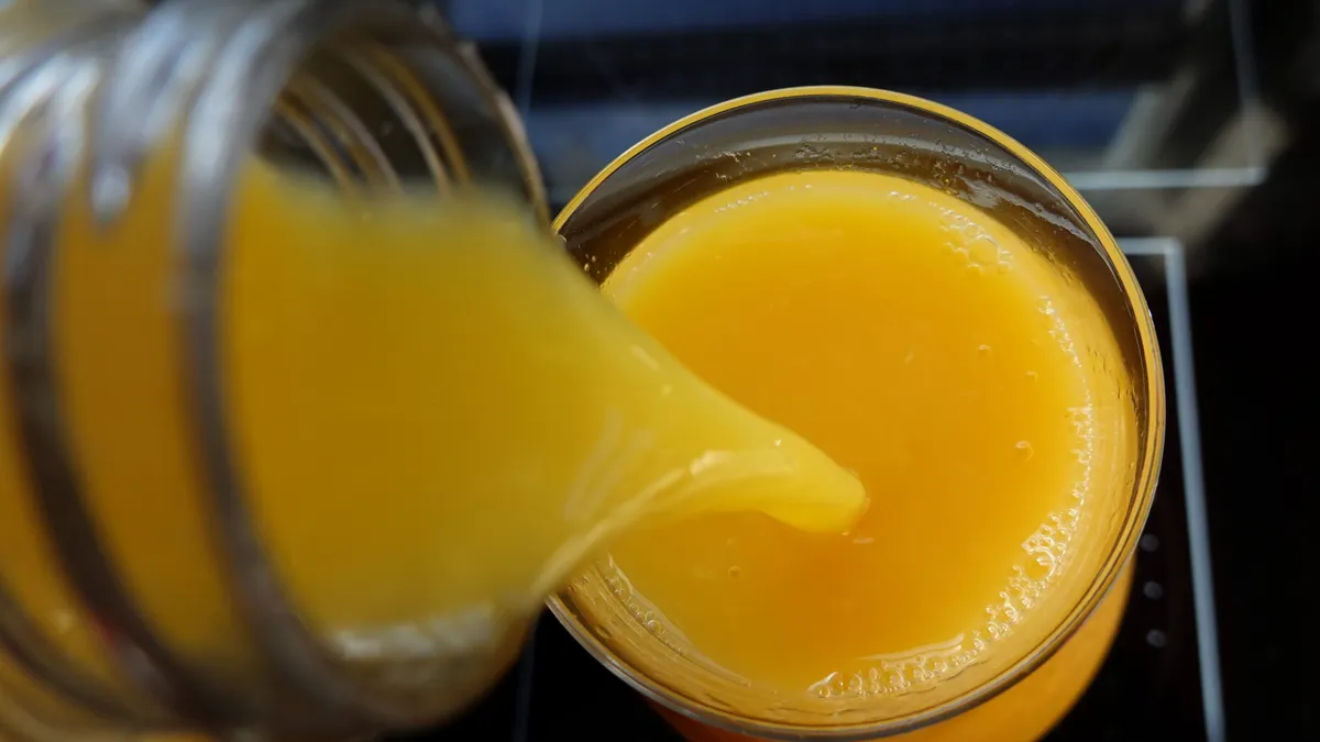 orange juice is poured into a glass