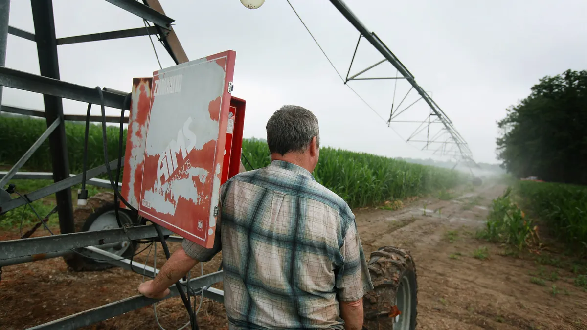 A farmer with his back to the camera looks at a field irrigation system