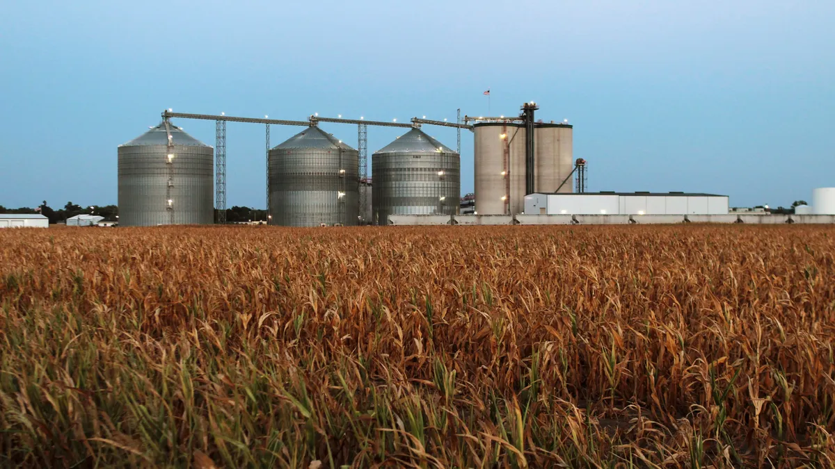 Corn is seen with an ethanol plant in the background.