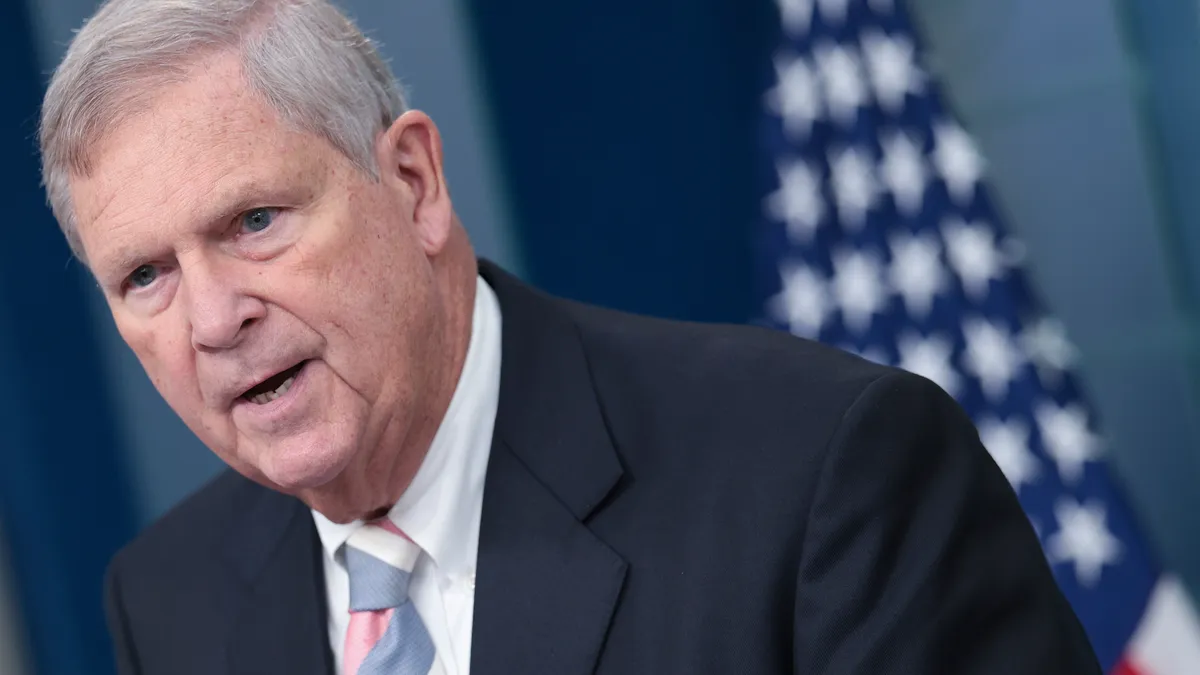 USDA Secretary Tom Vilsack speaks with an American flag in the background