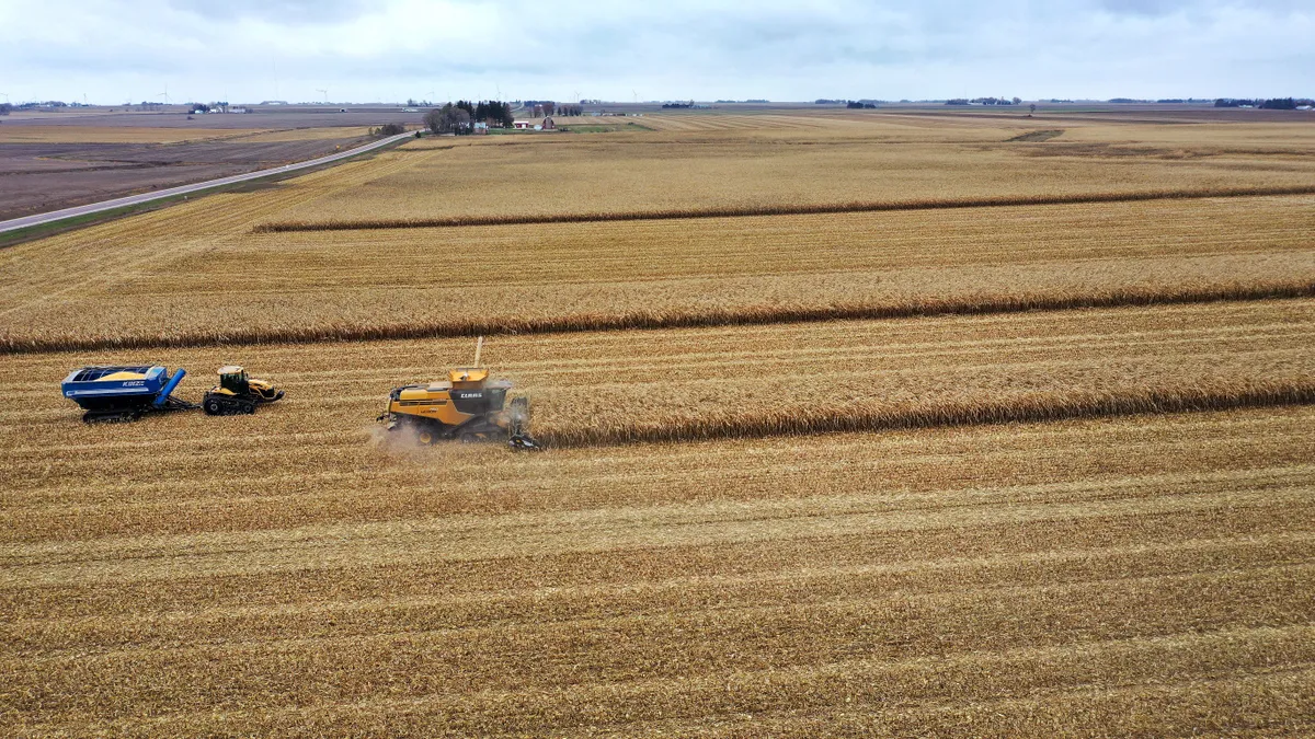 Tractors are seen in a corn field in an aerial shot.