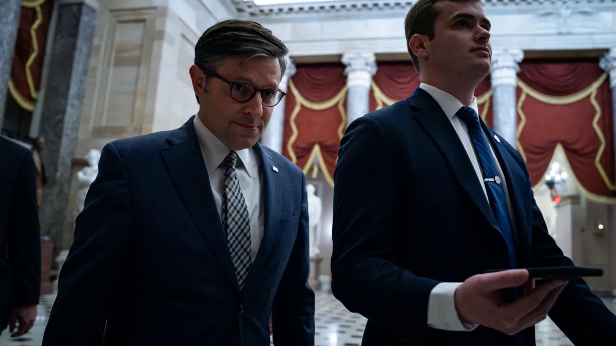 Two adults walk in hallway of U.S. Capitol building.