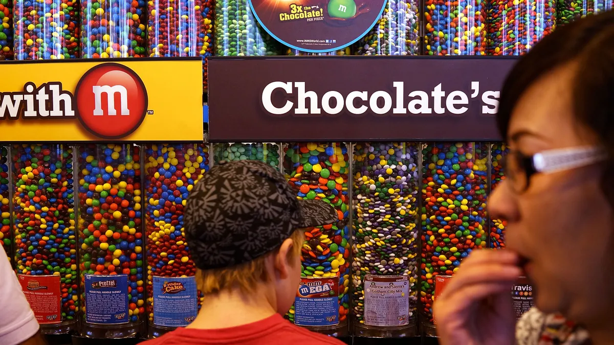 A boy is seen from behind as he looks at M&M candy dispensers.