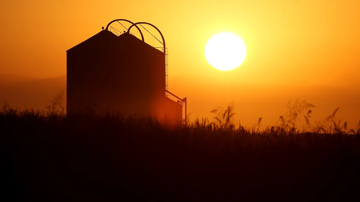 The silhouette of a grain elevator is seen as the sun rises.