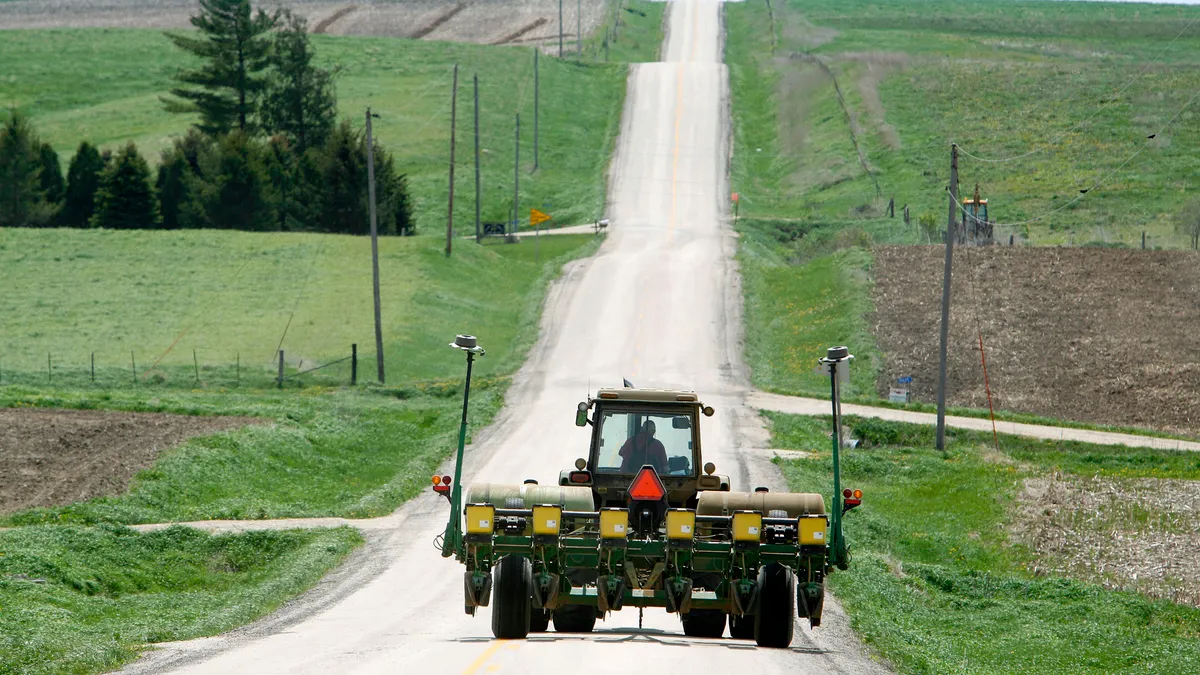 An Iowa farmer pulls a corn planter behind his John Deere tractor.