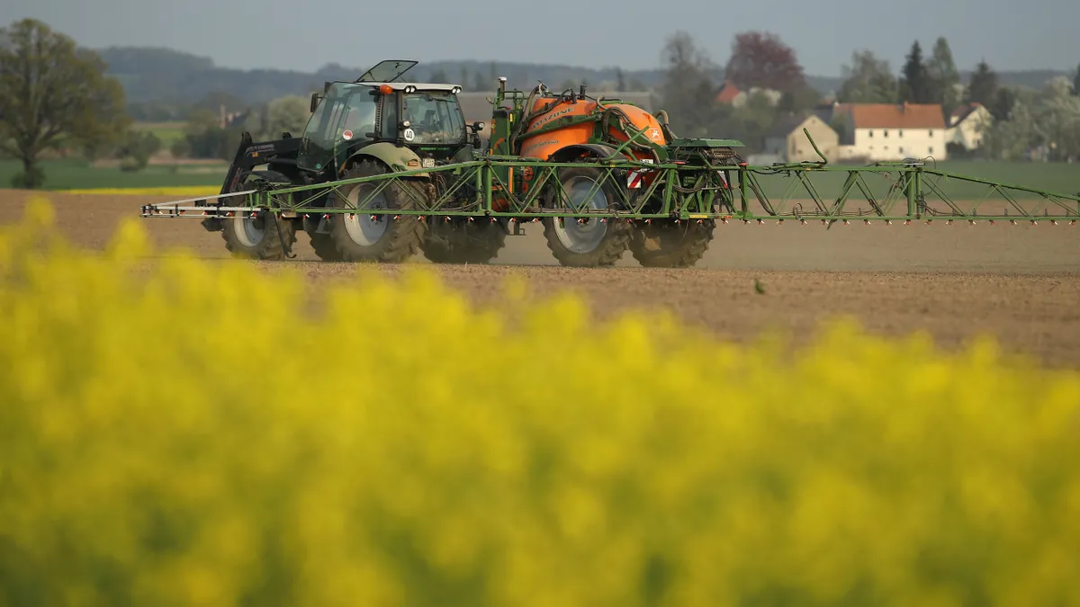 A tractor with a spray attachment is seen on a field.