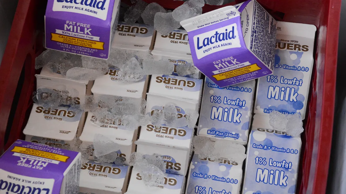 A cooler full of various brands of milk in half-pint containers.