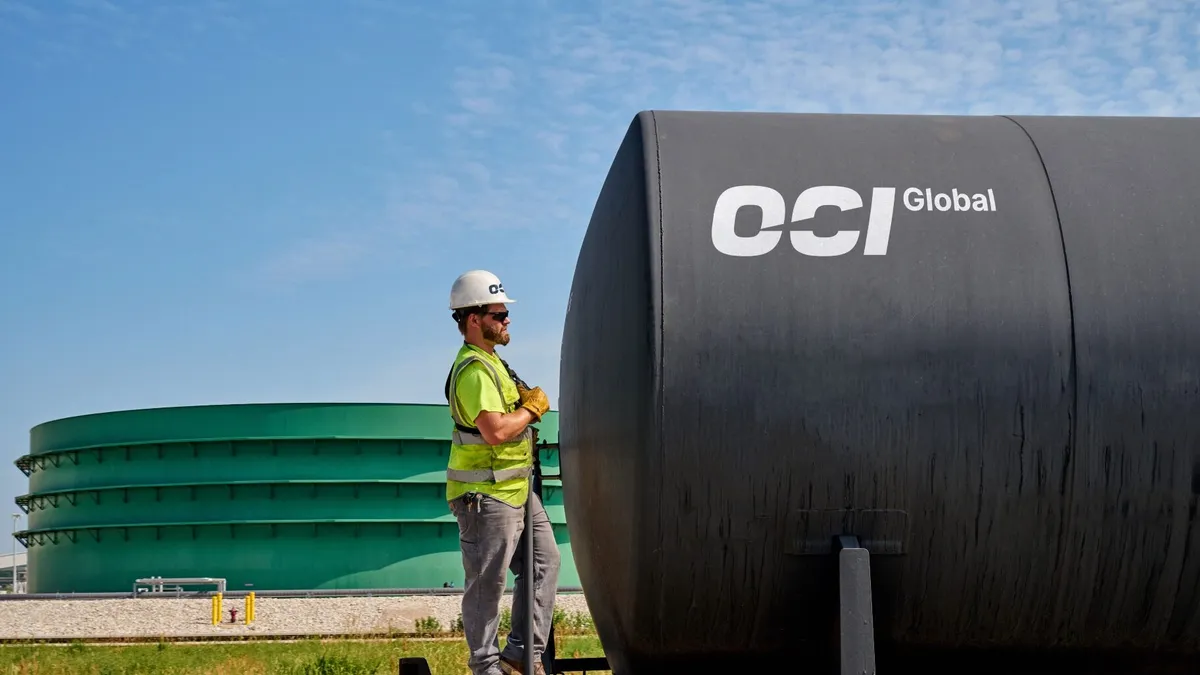 A hard-hat worker stands near OCI Global equipment.