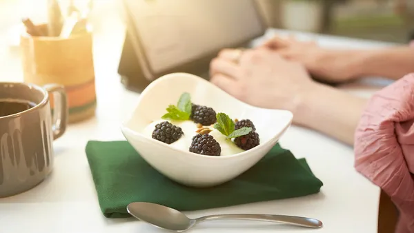 Berries are seen in a bowl next to a person sitting at a computer