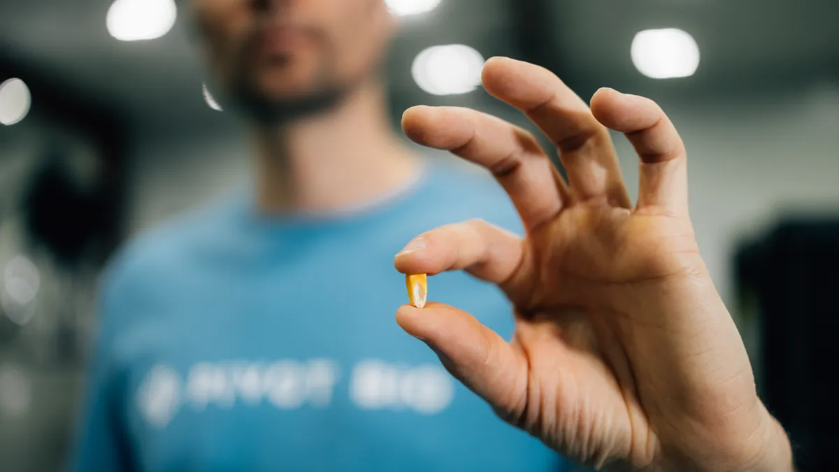 A person holds a corn kernel to the camera.