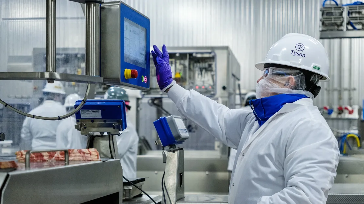 A woman in protective gear stands in front of a machine